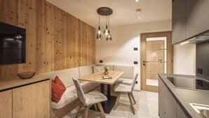 Une cuisine moderne agrémentée d’éléments en bois, un coin repas avec une table et des chaises, et un four encastré.