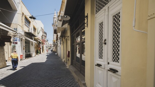 A narrow cobblestone street lined with buildings, featuring a woman walking down the path. - Home with Terrace in Heart of old Town of Chania (Chania)