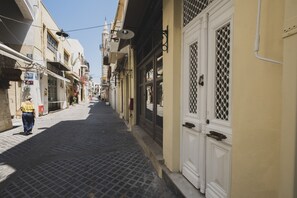 A narrow cobblestone street lined with buildings, featuring a woman walking down the path.