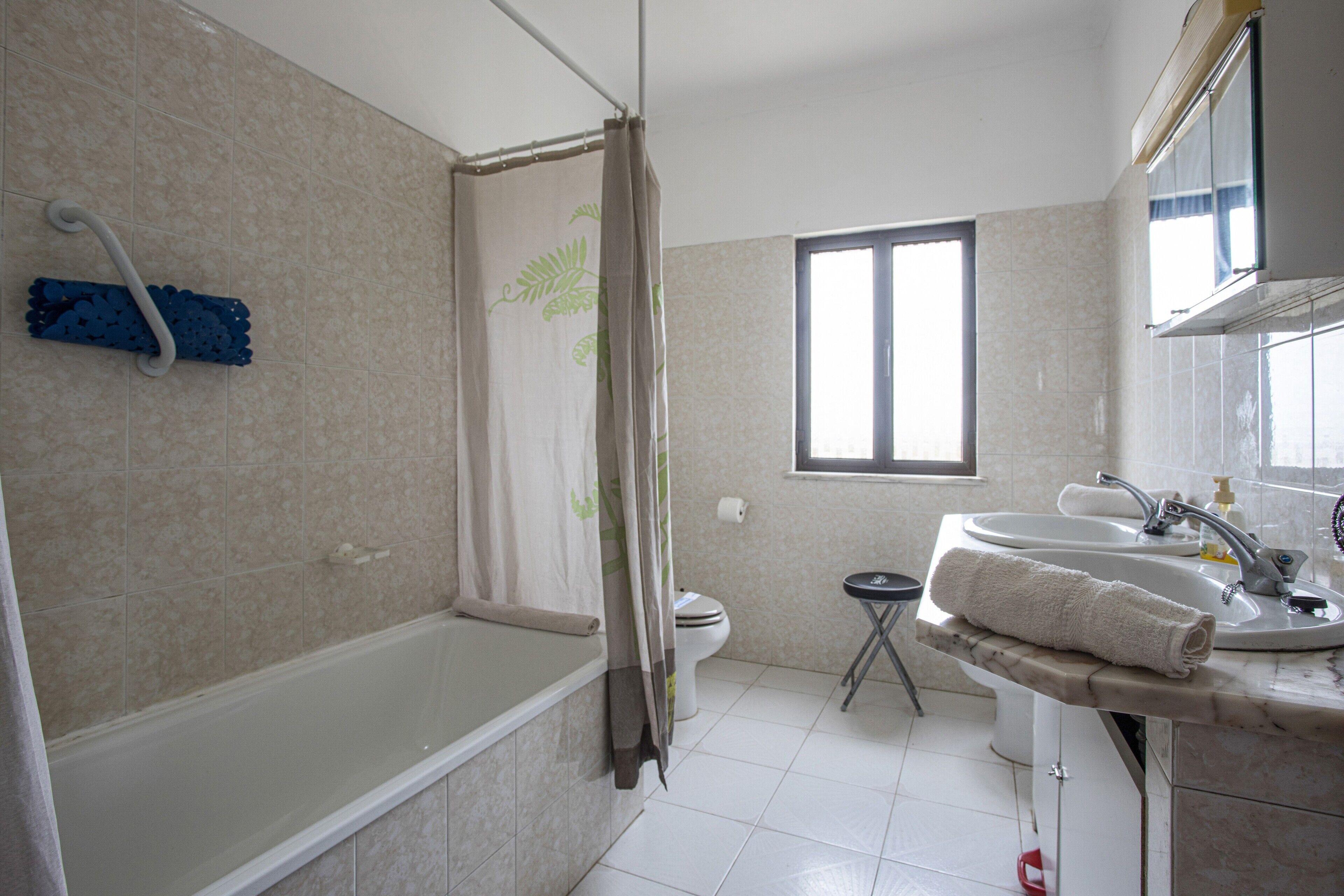 Un bagno con vasca, servizi igienici, lavandino e finestra.