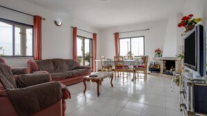 A living room with a sofa, dining table, chairs, a TV, and a fireplace.