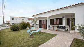A residential building with a patio, outdoor seating, and a small garden.