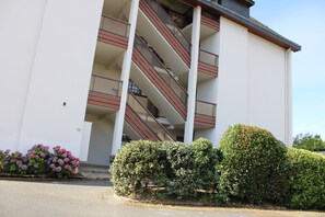 Un edificio moderno con facciata bianca, diversi balconi e una scala che conduce ai piani superiori.