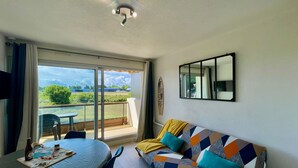 A living room with a sofa, a table with a bottle, and a mirror on the wall. - DES AILES - Apartment Port Haliguen - parking - 1bedroom (Quiberon)