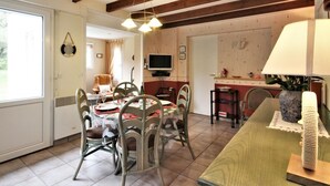 A dining area with a table and chairs, a television, and a kitchen area with a stove and sink.