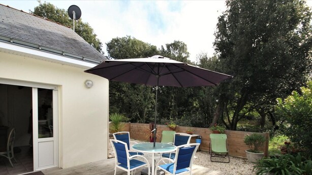 An outdoor patio with a table and chairs, a large umbrella, and a wooden deck.
