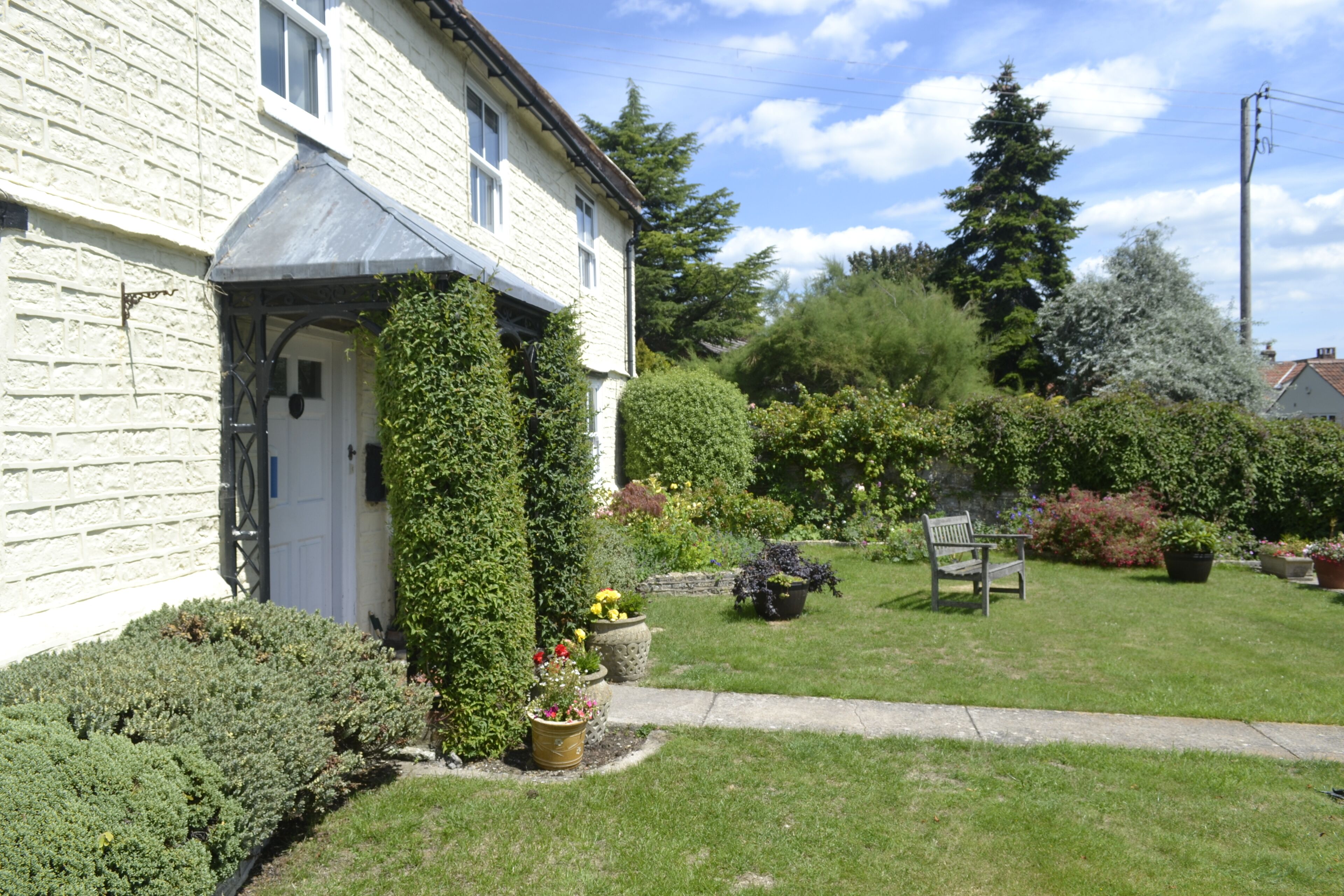 A white house with a garden, a bench, and a pathway.