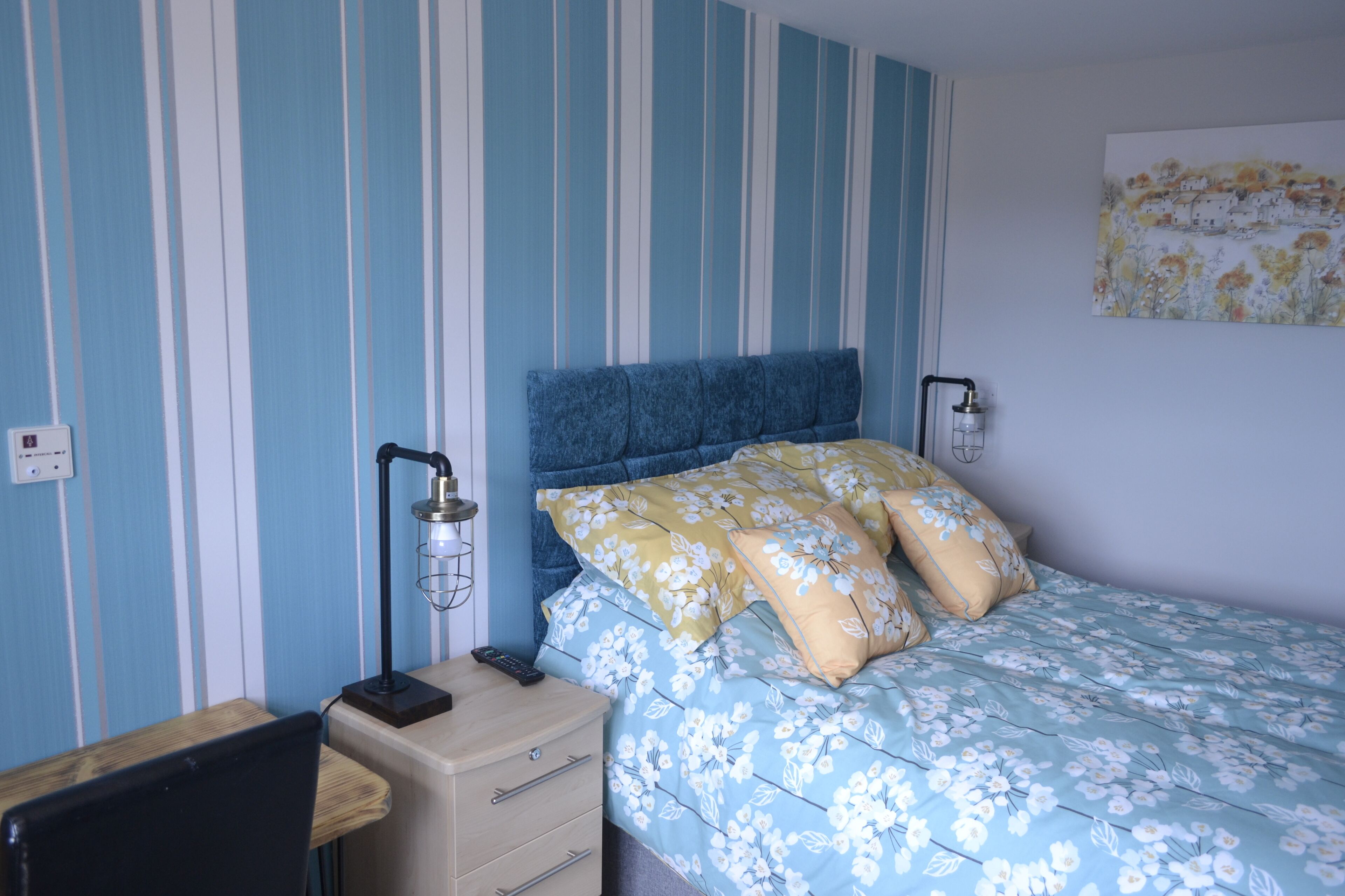 Een slaapkamer met een bed, een bureau en een stoel.