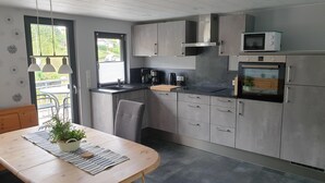 Una cocina moderna con gabinetes grises, encimera negra y electrodomésticos de acero inoxidable, incluyendo un microondas y un horno.