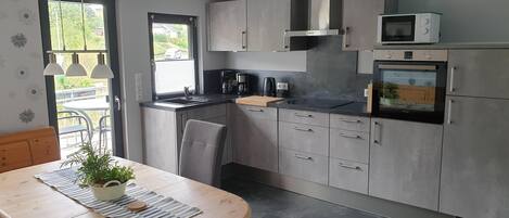 A modern kitchen with grey cabinets, a black countertop, and stainless steel appliances including a microwave and oven.