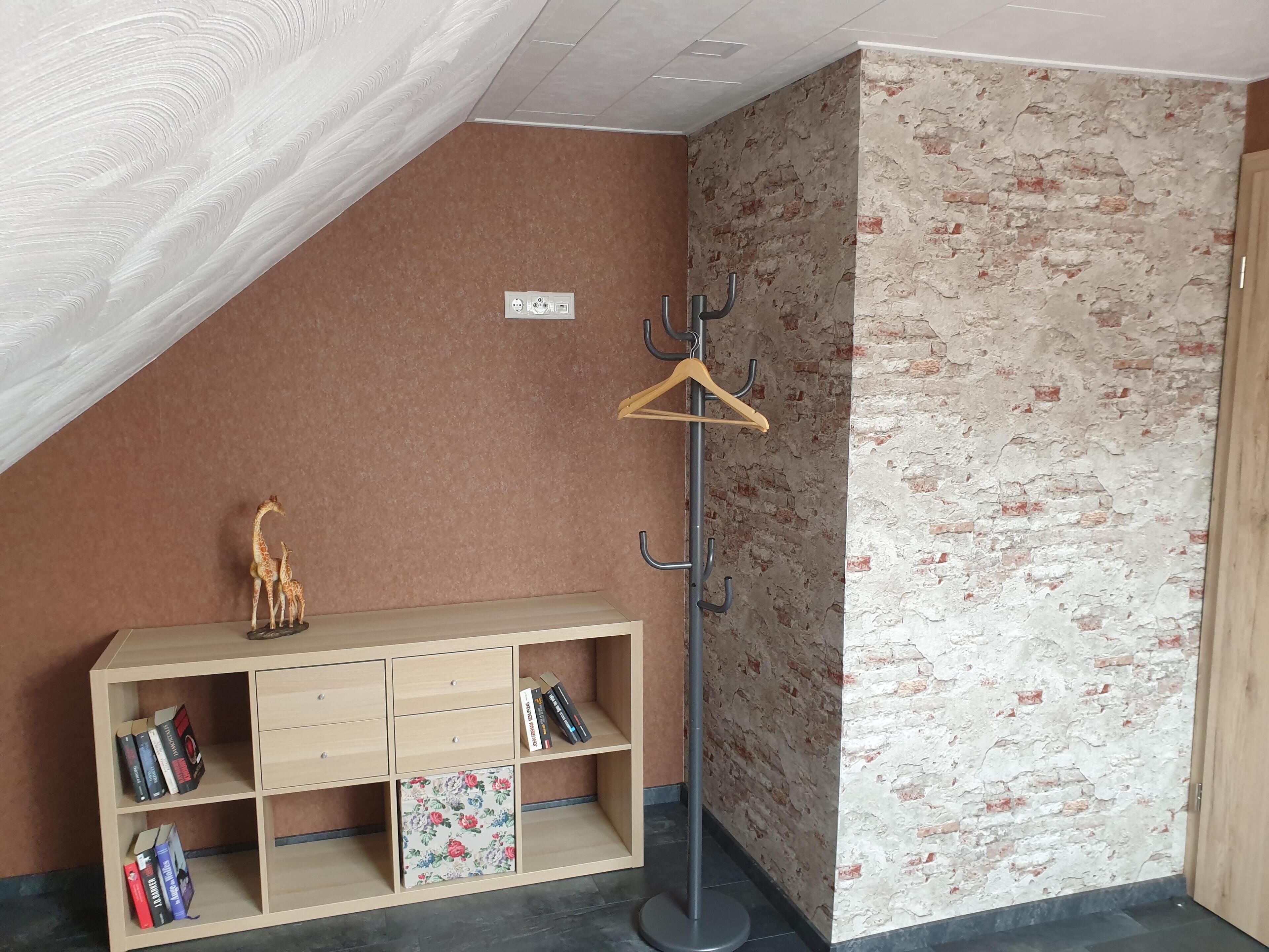 Een hoekzaak met een houten kast, boeken, een kapstok en een decoratieve giraffe.