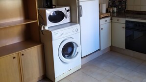 Una cocina compacta con lavadora, refrigerador y microondas.