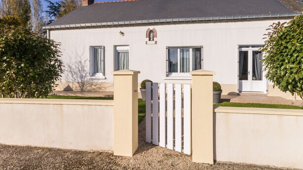 A white building with a grey roof, a gated entrance, and a small garden area. - Countryside Cottage with Private Terrace and Garden, Near Châteaubriant (Grand-Auverné)