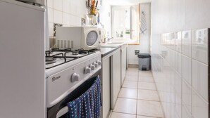A kitchen with white cabinets, a gas stove, a microwave, and a window. - Countryside Cottage with Private Terrace and Garden, Near Châteaubriant (Grand-Auverné)