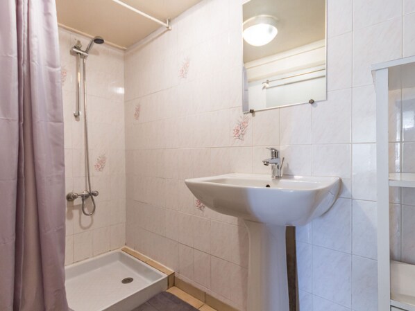 A bathroom with a shower, a sink, and a mirror.