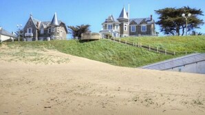 A coastal property with a sandy beach, a staircase leading to a house, and a clear blue sky. - Cottage in Tharon: 2 bedrooms, terrace, parking, near the sea (Saint-Michel-Chef-Chef)