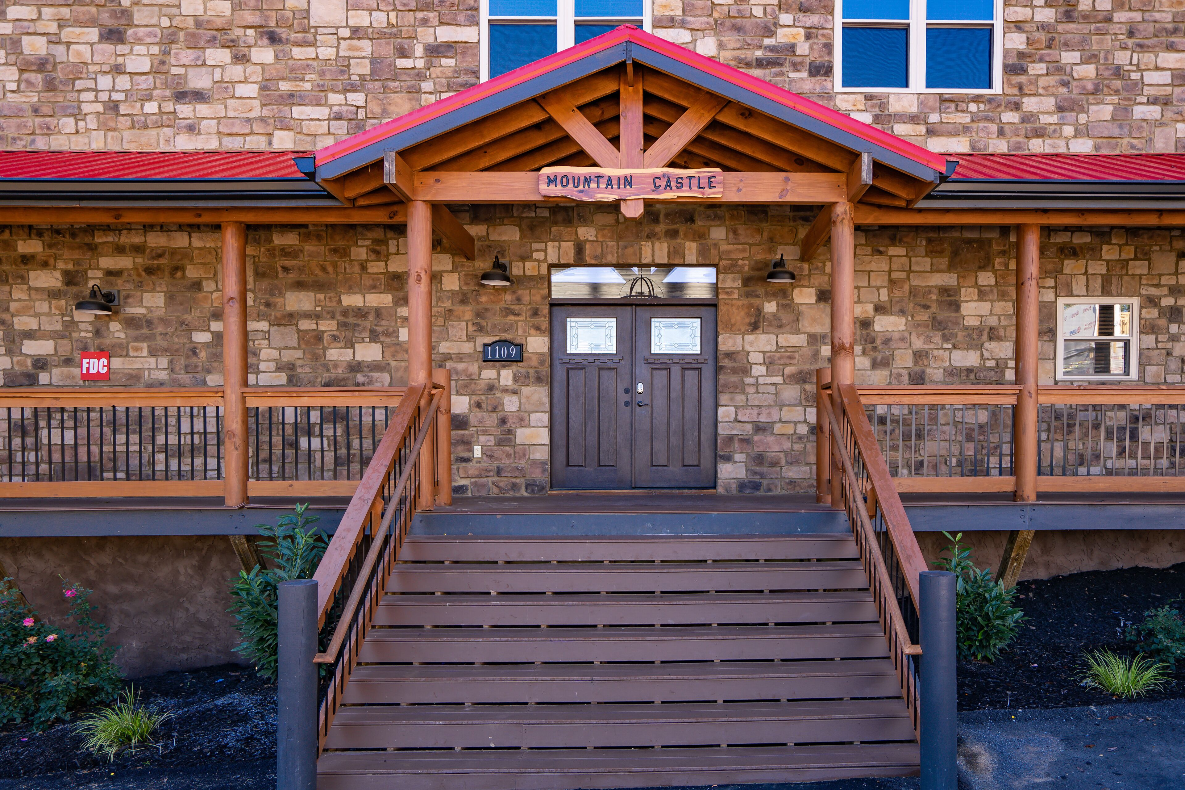 Un bâtiment en pierre avec une entrée en bois, une enseigne indiquant « Château de montagne » et un escalier menant à la porte.