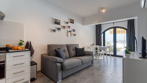 A modern living room with a grey sofa, a white dining table, and a kitchen area with a countertop and cabinets. - Apartment with amazing views & terrace - garden (PATALAVACA)