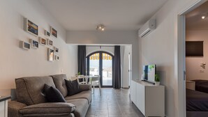 A modern living room with a sofa, a TV, and a dining area with a table and chairs. - Apartment with amazing views & terrace - garden (PATALAVACA)
