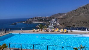 A swimming pool with sun loungers and a view of the sea and buildings in the background. - Apartment with amazing views & terrace - garden (PATALAVACA)