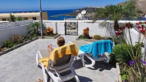 A balcony with two lounge chairs, one with a yellow towel and the other with a blue towel, overlooking a coastal view with buildings and a clear sky. - Apartment with amazing views & terrace - garden (PATALAVACA)