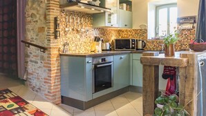 Une cuisine compacte dotée d’un plan de travail recouvert de carreaux, d’un four à micro-ondes, d’une bouilloire et d’un petit four.