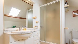 A bathroom with a white sink, mirror, and a shower enclosure. - Charming Cottage with Fireplace, Mezzanine, and Garden near Guérande (Saint-Molf)