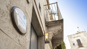 A building facade with a plaque, a light fixture, and an arched window.