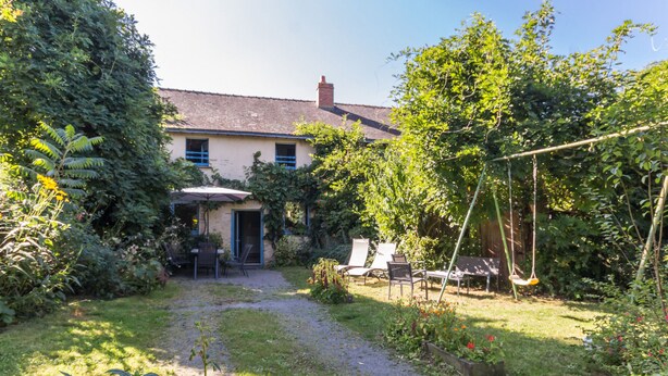 Ein Haus mit Garten, Schaukel und Terrasse mit Gartenmöbeln.