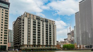 Un immeuble moderne à plusieurs étages, doté de nombreux balcons, situé au bord d’une rivière.