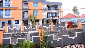 A multi-story building with balconies, a gated entrance, and a small garden area. - Glads Apartment (Kigali)