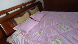 A bed with a floral-patterned pink bedspread and two pillows. - Glads Apartment (Kigali)