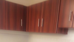 A kitchen with wooden cabinets and a granite countertop. - Glads Apartment (Kigali)
