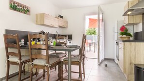 A modern kitchen with wooden cabinets, a dining table with chairs, and a view to the outside.
