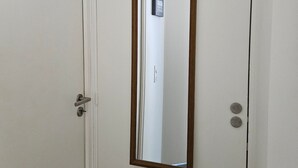 A closed door with a wooden frame and a metal handle, a mirror reflecting a door handle and a sign on the wall.