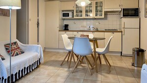 A compact kitchen with a dining area, featuring a microwave, stove, and cabinets. - Waterfront 2-Bedroom Cottage with Terrace in Saint-Michel-Chef-Chef (Saint-Michel-Chef-Chef)