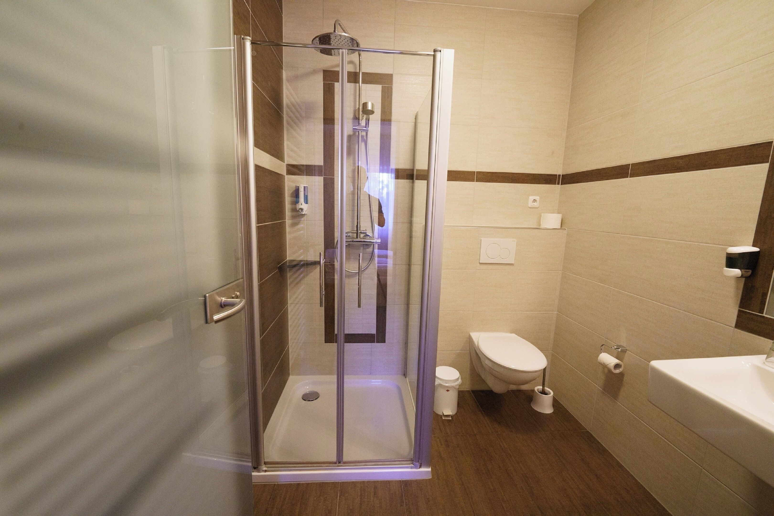 Een moderne badkamer met een douche met glazen wand, toilet en wastafel.