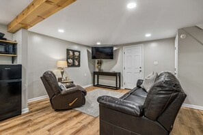 A living room with a flat-screen TV, a recliner, a coffee table, and a refrigerator. - Mill Creek Guest-Suite Nolensville-Brentwood, Tn (Nashville)