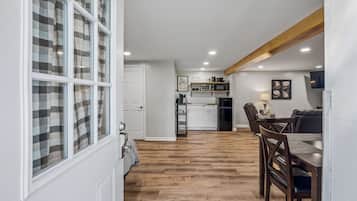 Une cuisine moderne avec des meubles blancs, une table à manger en bois et un réfrigérateur noir.