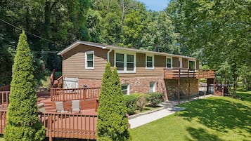 A two-story house with a covered patio, a brick section, and a lawn.