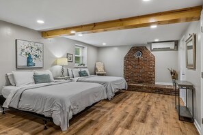 Un dormitorio con dos camas, una pared de ladrillo y una viga de techo de madera.
