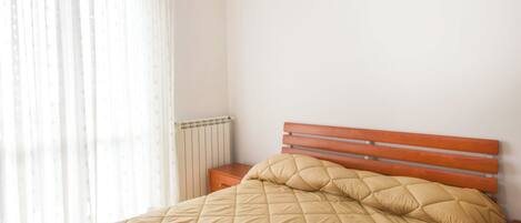 A bedroom with a bed, wooden headboard, and a radiator.