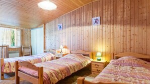 Een gezellige kamer met houten wanden en vloeren, met twee bedden en bijpassende hoofdeinden en nachtkastjes met lampen.