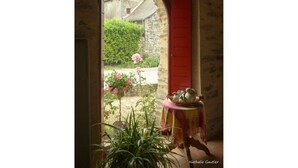 A doorway leading to a garden with a table and potted plants. - Spacious Country House with Private Pool and Enclosed Garden (Pannecé)