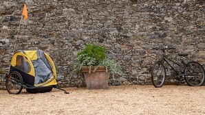 Un mur de pierres, un vélo et une poussette de camping.