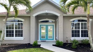 A two-story house with a front door, two windows on the ground floor, and a small porch area. - Privacy in Paradise (CapeCoral)