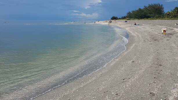 A beach with clear water, pebbles, and a few people. - Privacy in Paradise (CapeCoral)