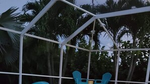 An outdoor pool area with a covered seating area, two candles on a table, and starfish decorations. - Privacy in Paradise (CapeCoral)