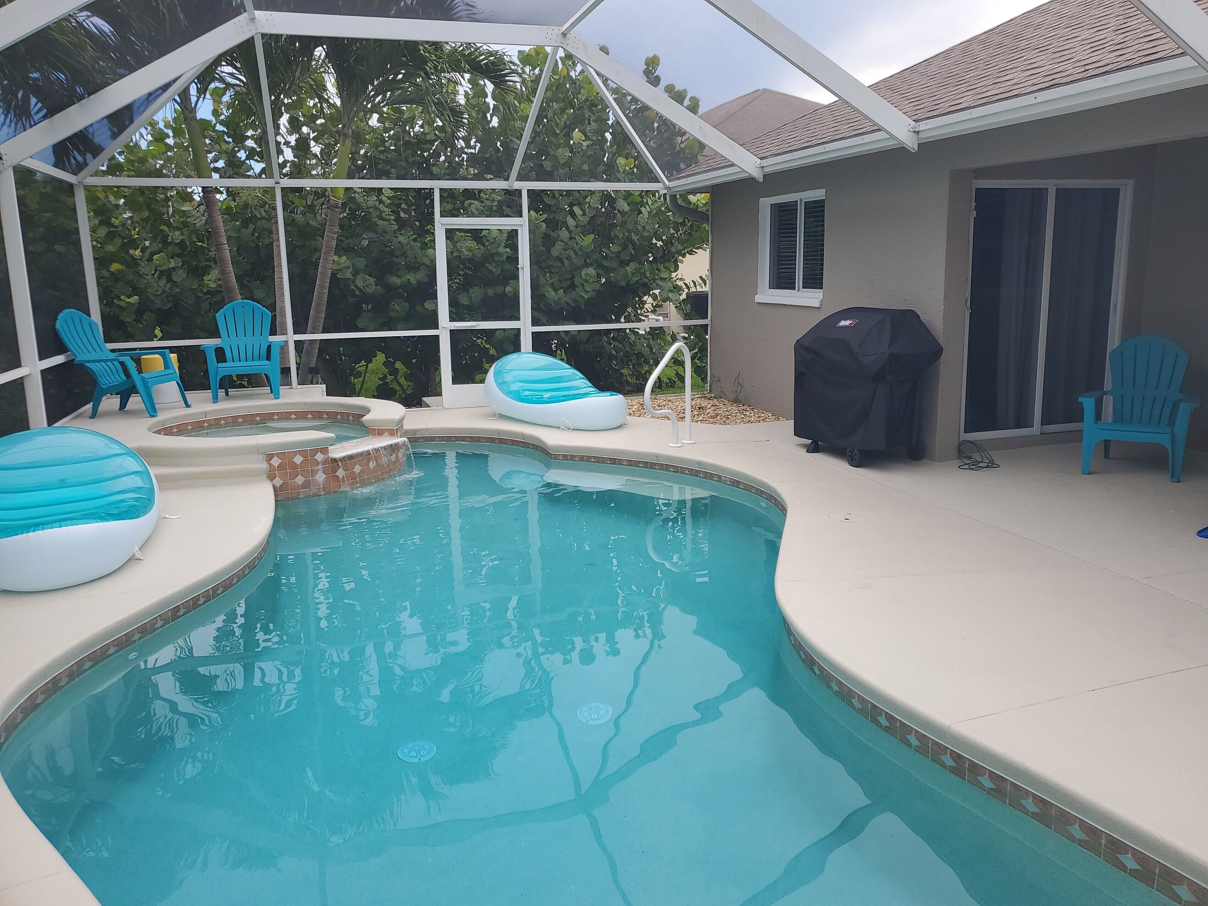Une piscine avec des chaises bleues et un barbecue.