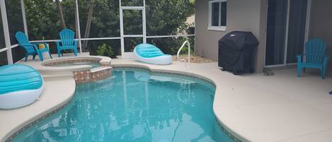 Une piscine avec des chaises bleues et un barbecue.